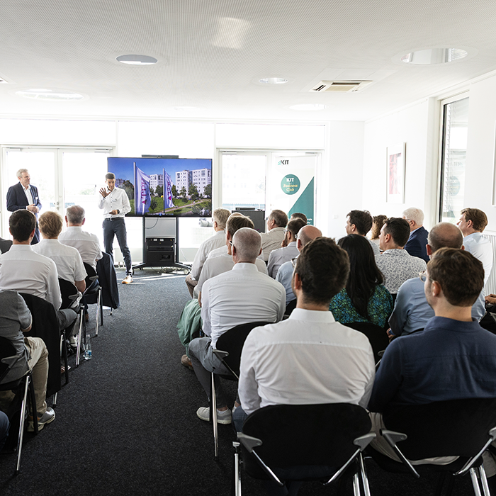 A speaker presenting a digital image to an audience in a seminar room.