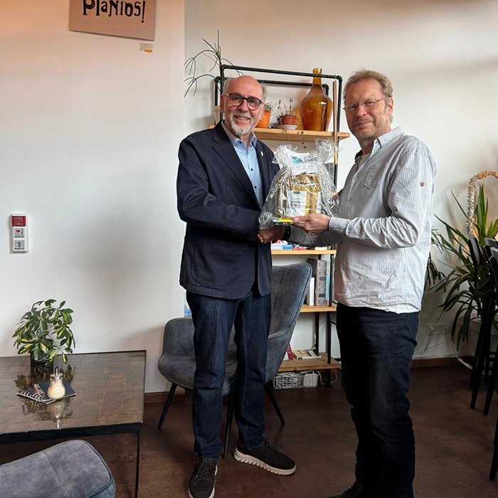 2 men, posing thogether and holding a present